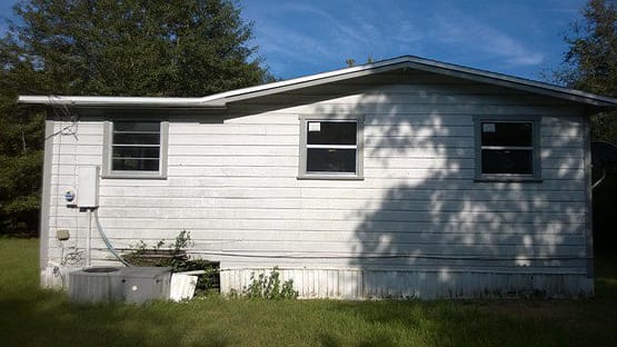 A white house sitting in the grass near some trees.