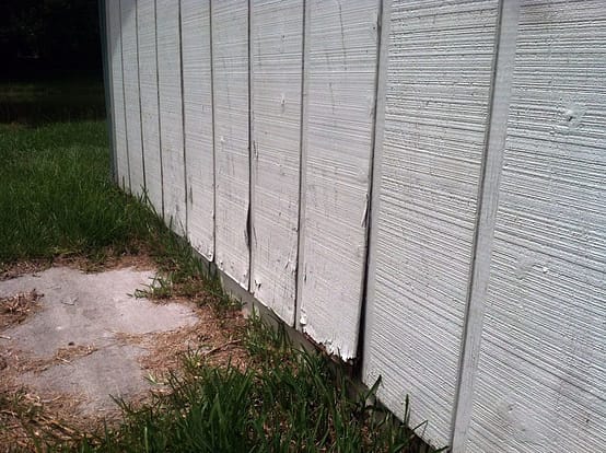 A white fence with grass growing on it.