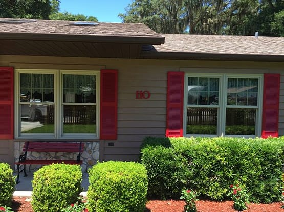 A house with bushes and trees in front of it