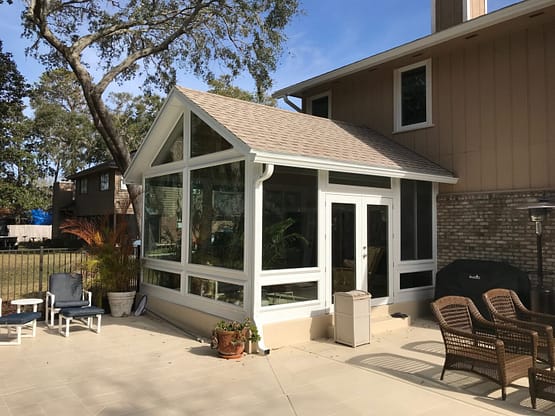 A white sunroom with a porch and patio furniture.