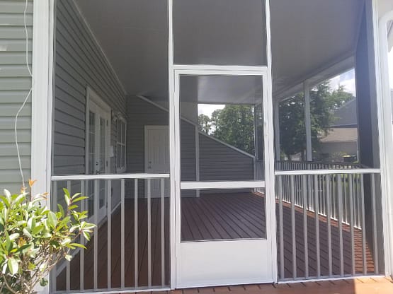 A porch with a screen door and railing.