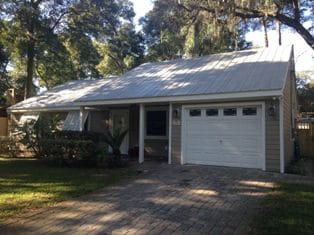 A white garage door is open in front of a house.