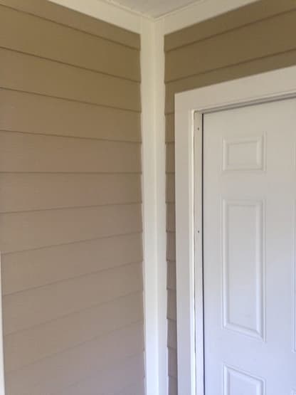 A white door and some wood paneling on the outside of a house.