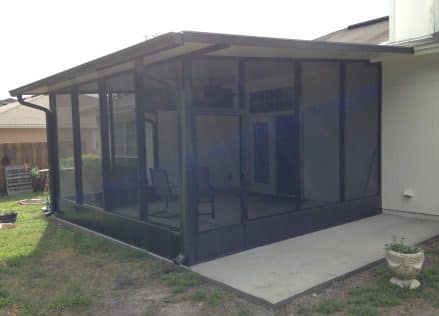 A patio enclosure with a screen door and a concrete walkway.