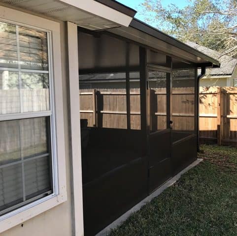 A black screen door is open to let in the sun.