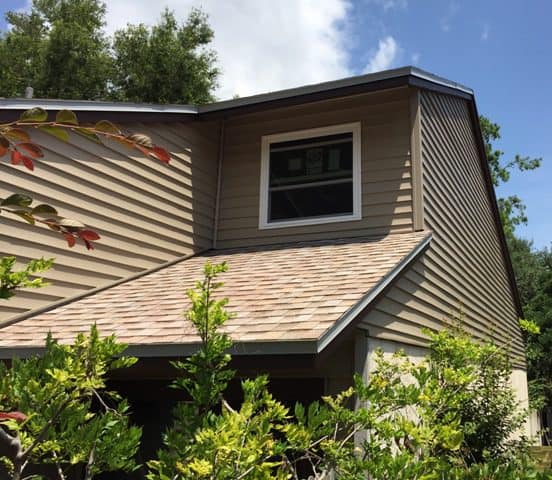 A brown house with a window and bushes