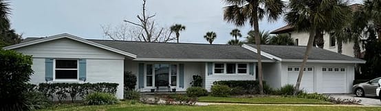 A house with trees in the background and grass on the front lawn.