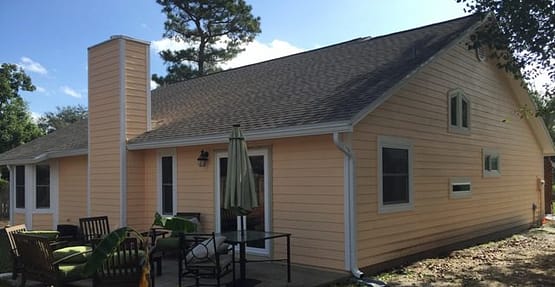 A yellow house with a table and chairs outside.