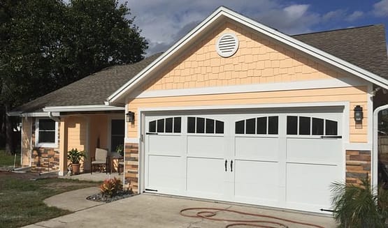 A yellow house with two white garage doors.