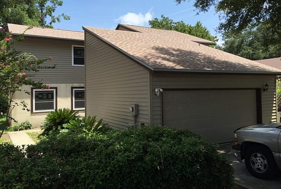 A house with a garage and trees in the background.