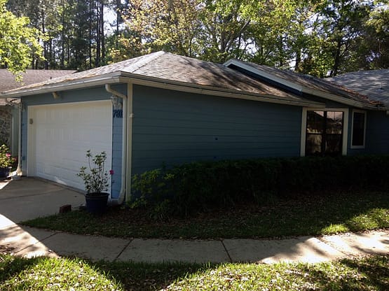 A house with a driveway and trees in the background.