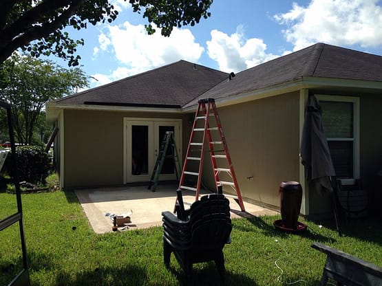 A house with a ladder and some tools on the ground.