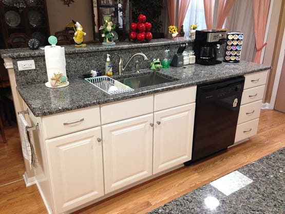 A kitchen with white cabinets and black counter tops.