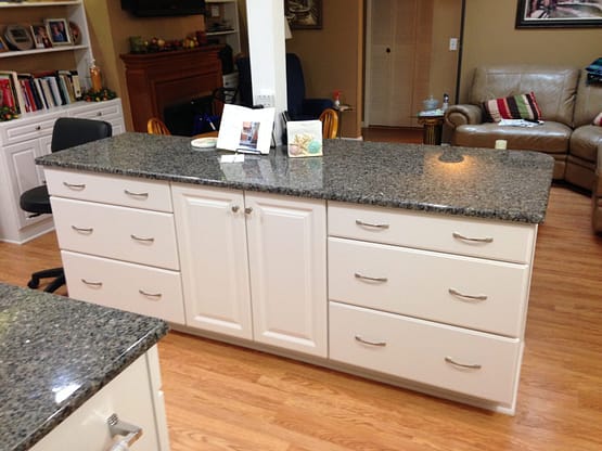 A kitchen with white cabinets and granite counter tops.