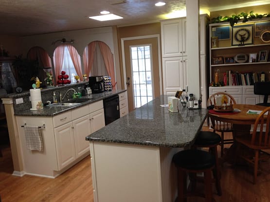 A kitchen with granite counter tops and white cabinets.
