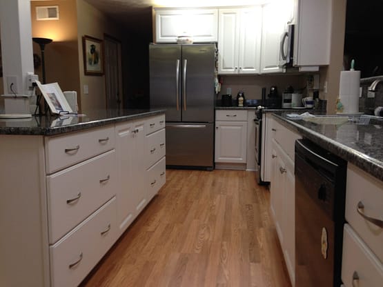 A kitchen with white cabinets and black counter tops.