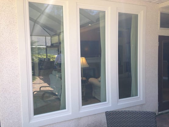 Three windows in a room with a couch and table.