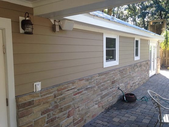 A cat sitting on the side of a house.