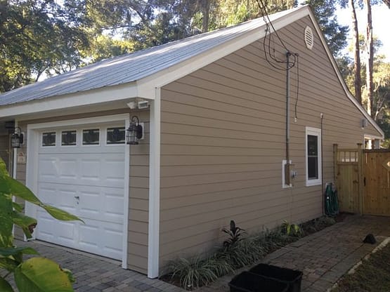 A garage with a white door and a brown roof.