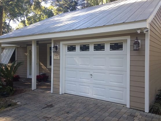 A white garage door sitting on top of a brick driveway.