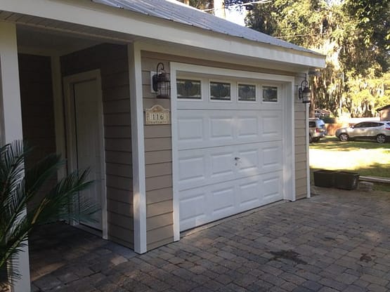 A white garage door is open and has windows.