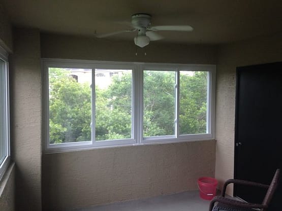 A room with two windows and a ceiling fan.