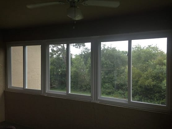 A room with several windows and trees outside.