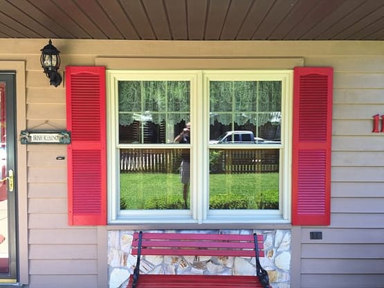 A red and white bench sitting in front of a window.