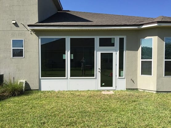 A house with a large lawn and sliding glass doors.