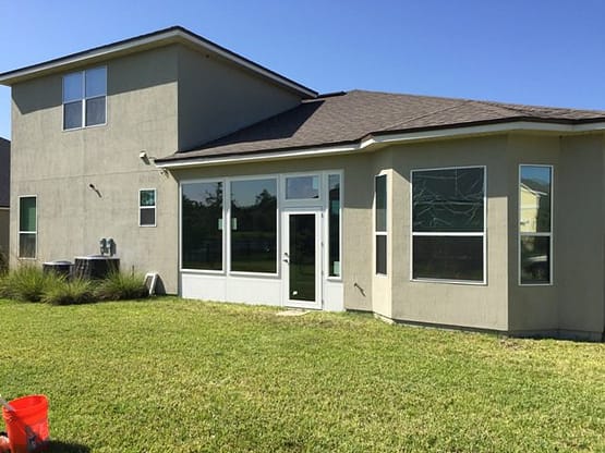A large house with lots of windows and grass.