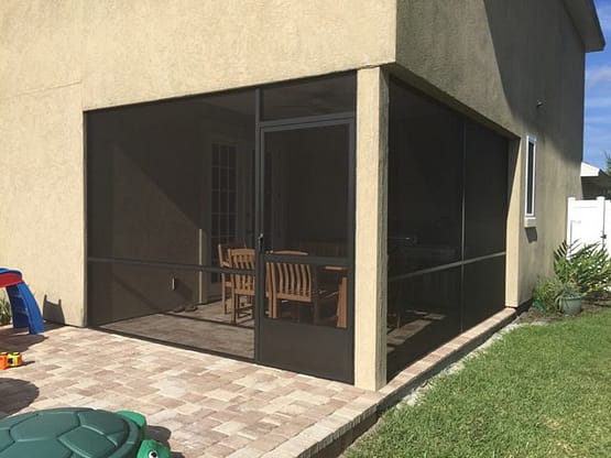 A patio with a screen door and an outside view.