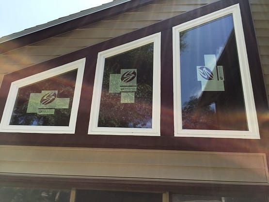Three windows in a house with the same color on each window.