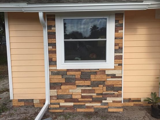 A window with a brick wall and a gutter.