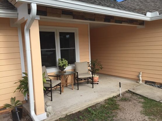 A patio with two chairs and table outside.