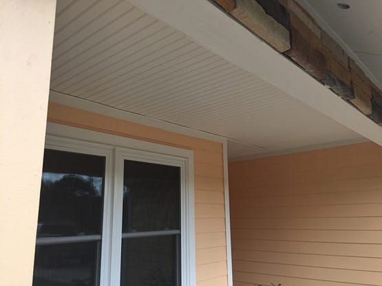 A porch with an open window and a ceiling.