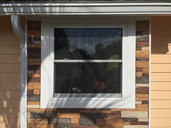 A window with a white frame and a brick wall.