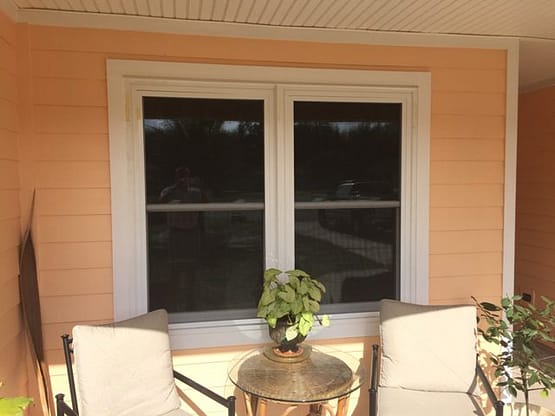 A table and chairs outside of a window.