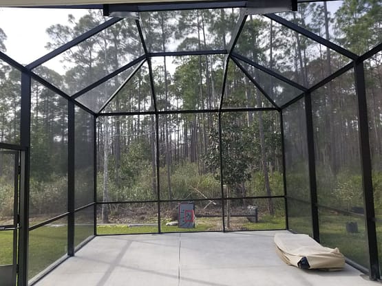 A large glass gazebo with trees in the background.
