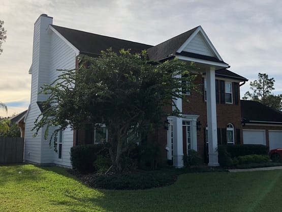A large white house with a tree in front of it.