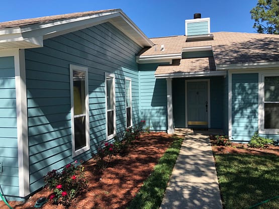 A blue house with a walkway leading to the front door.