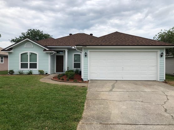 A house with a driveway and grass in front of it.