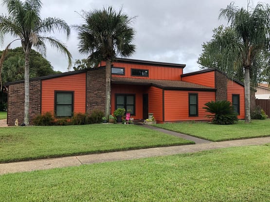 A house with a lawn and palm trees in the background.