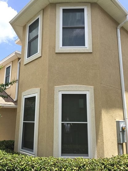 A tan building with three windows on the side.