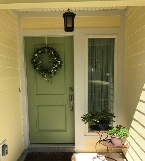 A green door with a wreath hanging on it.