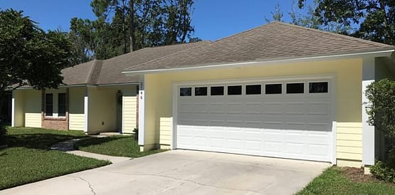 A white garage door in front of a house.