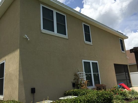 A house with two windows and a flower bed.