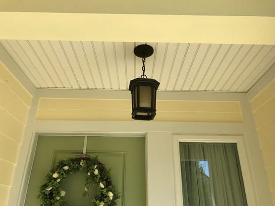 A porch light hanging from the ceiling of a house.