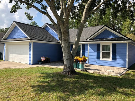 A blue house with a tree in front of it.