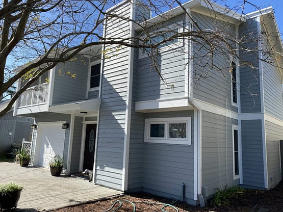 A house with a large driveway and trees in the background.